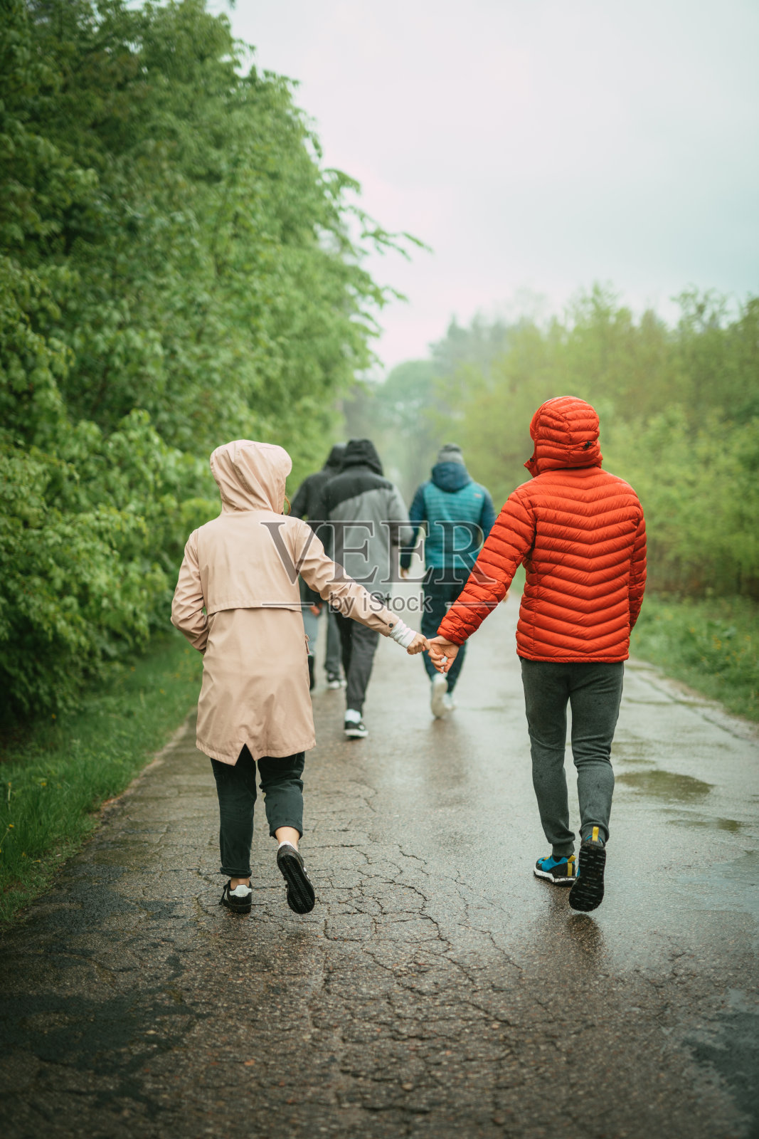 多雨的,夏天的一天。一群朋友走在潮湿的路上照片摄影图片