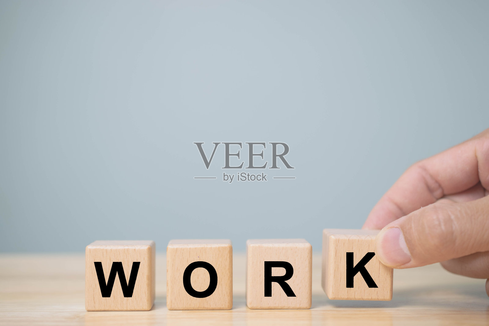 投资者的手把一个写着“工作”的木方块放在木桌上。概念工作在家，计划购买物业。选择最好的。照片摄影图片