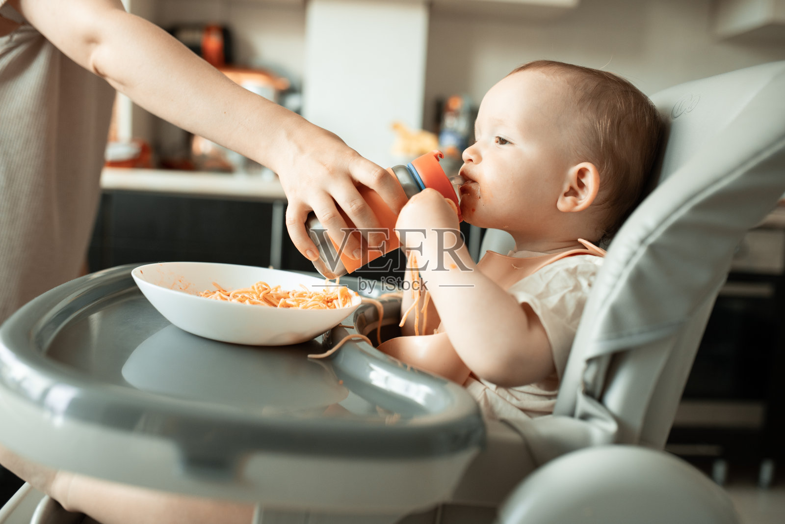 一位妇女的母亲给她的孩子一瓶水。照片摄影图片