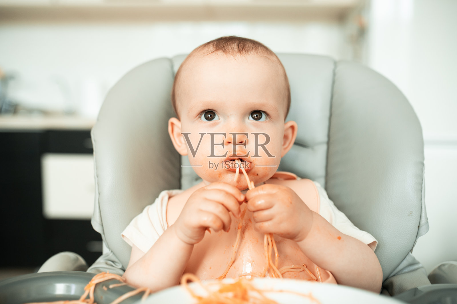 可爱的小男孩在吃意大利面时把厨房弄得一团糟照片摄影图片