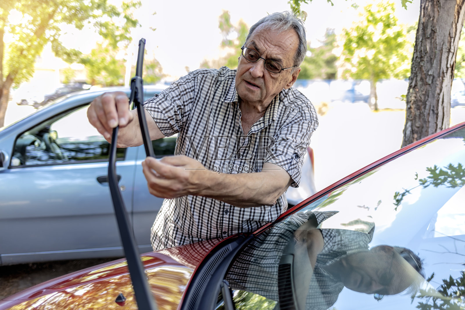 一位年长的白人男子在出发前检查他的挡风玻璃雨刷。照片摄影图片