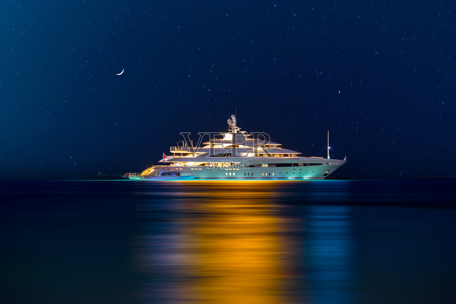 蓝色时刻：海湾上白色游艇的彩色灯光照片摄影图片