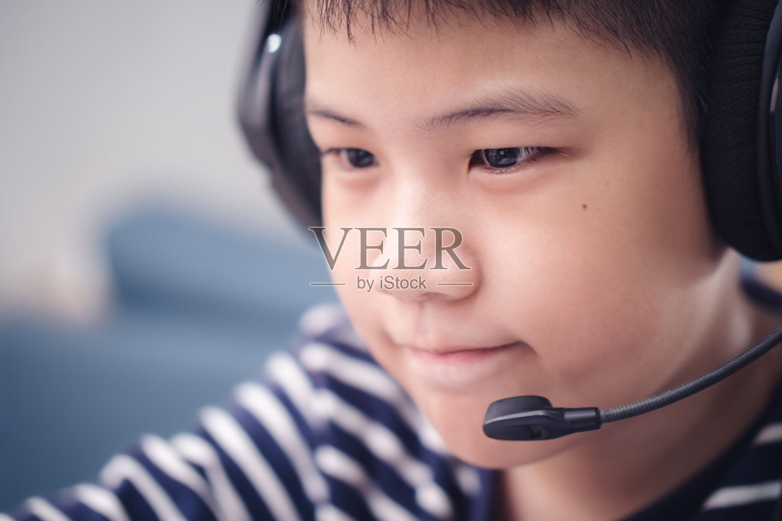 新常态特写面对亚洲男孩在线学习看着屏幕笔记本电脑开心的微笑和在家里的乐趣。技术教育理念，在家办公照片摄影图片