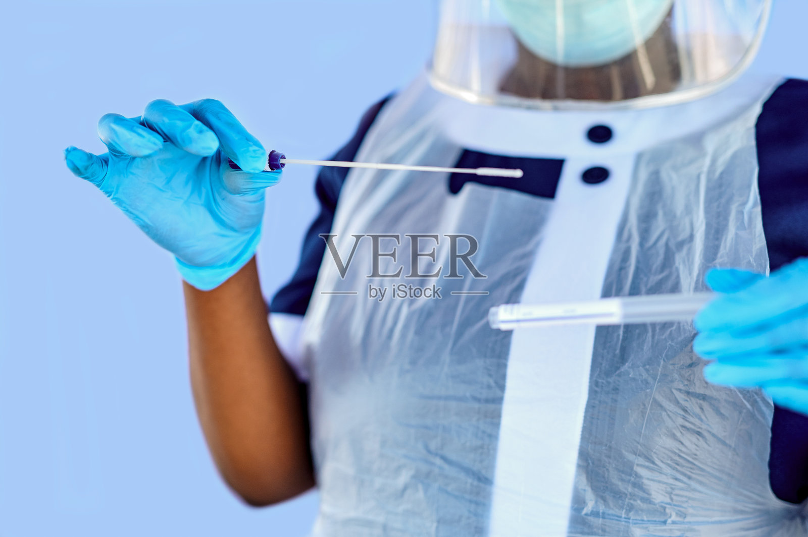 一名蒙面护士在蓝色背景下拿着棉签的剪影照片摄影图片