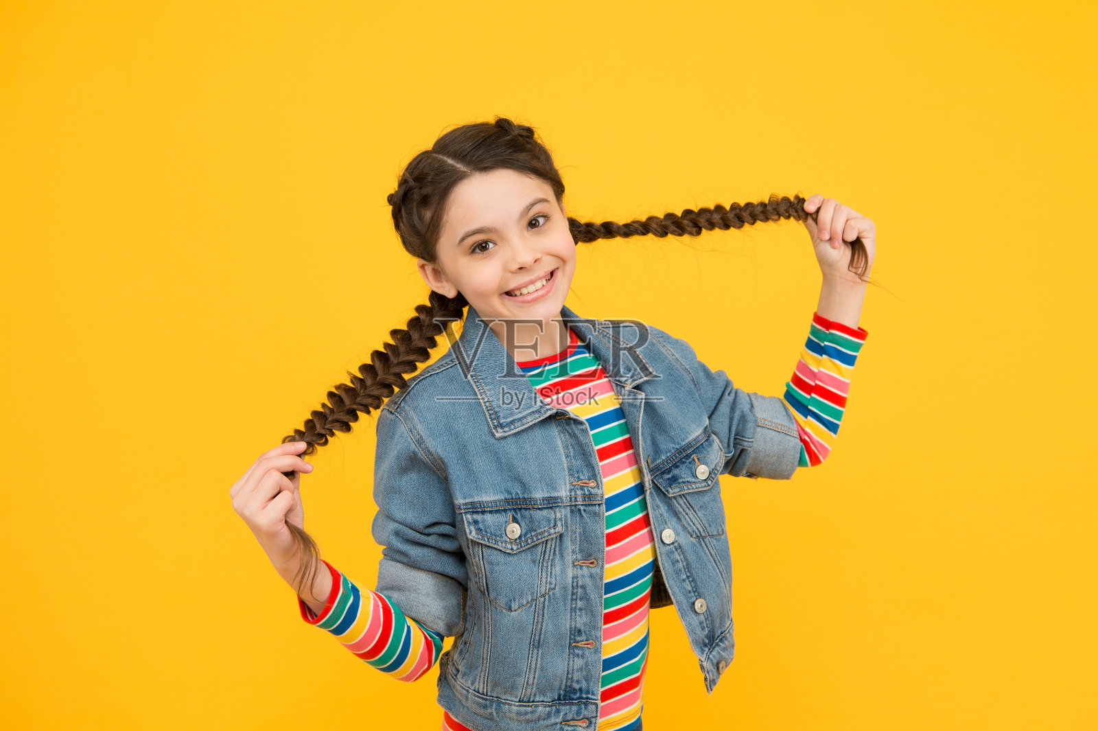 当我的头发长了，我就去理发。快乐的孩子挽着长发。扎着辫子的小女孩。时髦的发型。长发生长兴奋剂。自然的头发。沙龙护发照片摄影图片