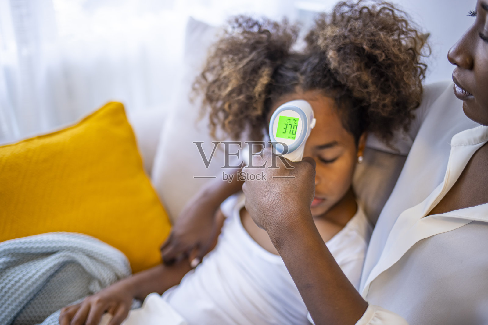 母亲在检查卧病在床的女儿。照片摄影图片