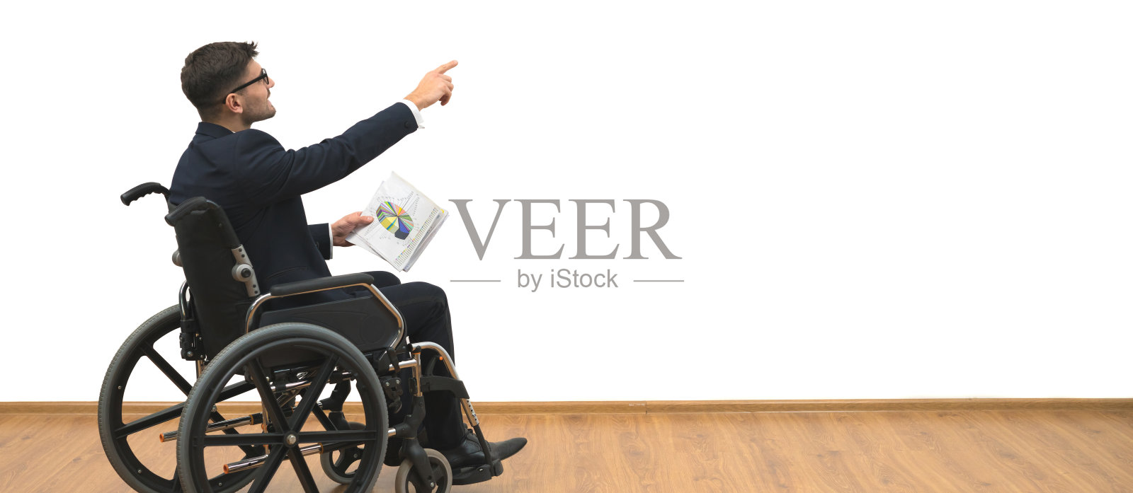 坐在轮椅上的残疾人在白色墙壁的背景上做手势照片摄影图片