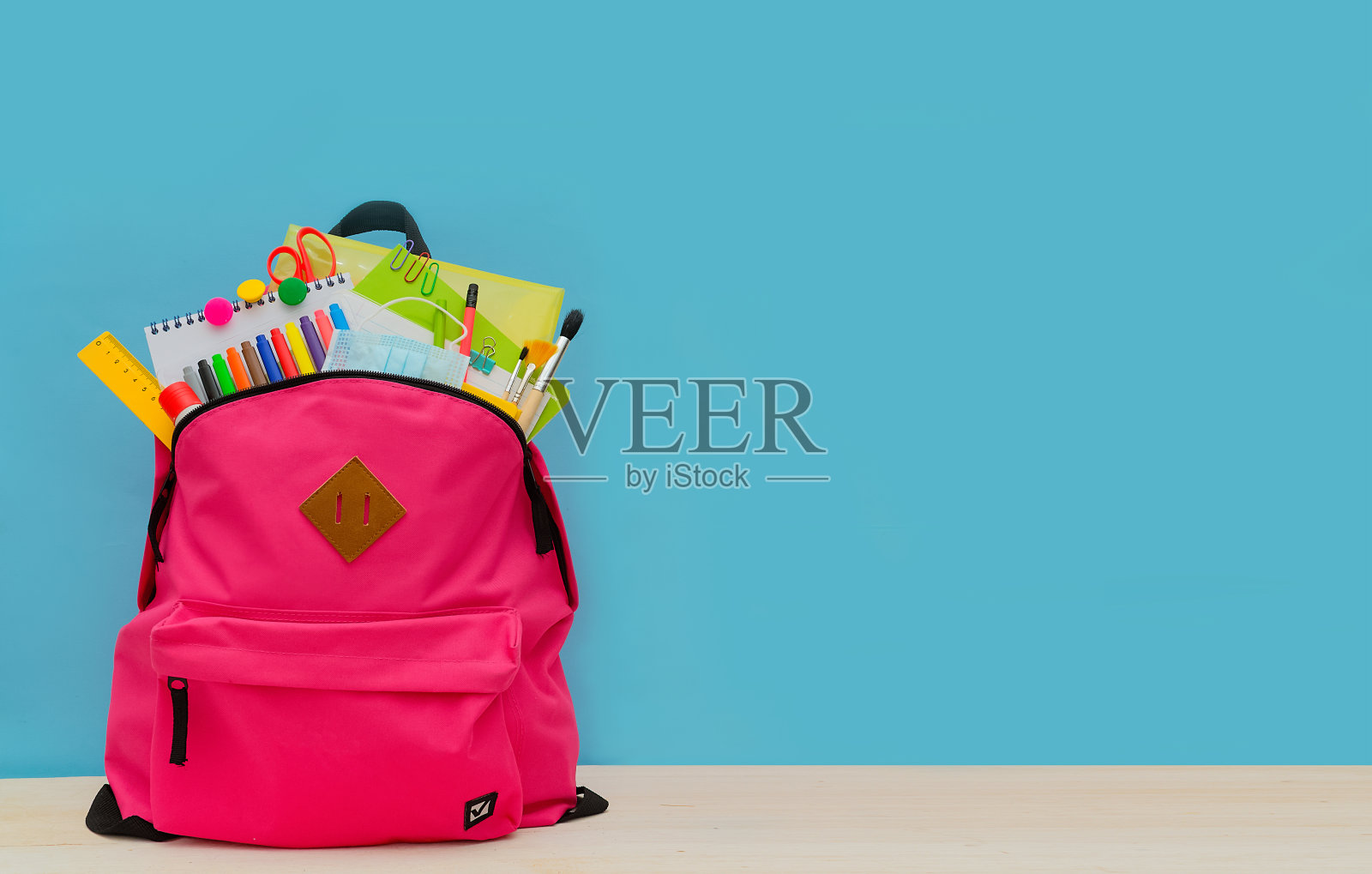 回到学校。学校或大学的背包，以蓝色为背景，色彩鲜艳的学校用品。用于学校儿童学习的文具。贺卡或横幅出售。Copyspace。照片摄影图片