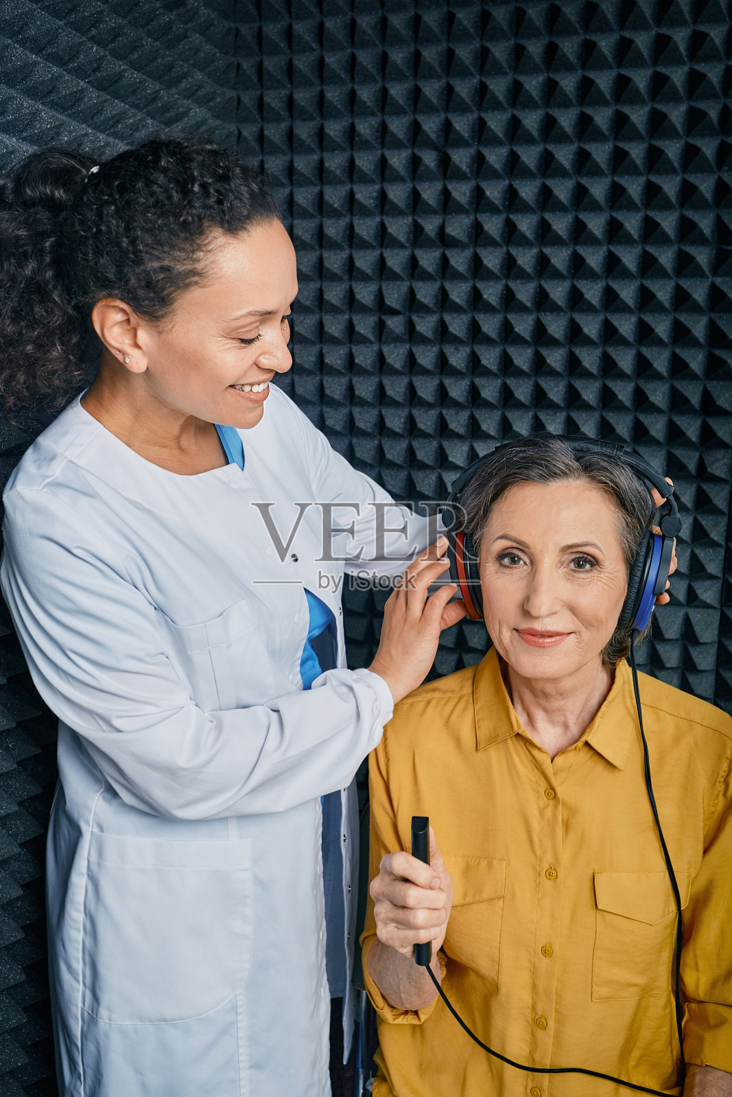 听力测定。听力专家在隔音听力舱为一位成熟女性做听力检查。纯音听力图测试照片摄影图片