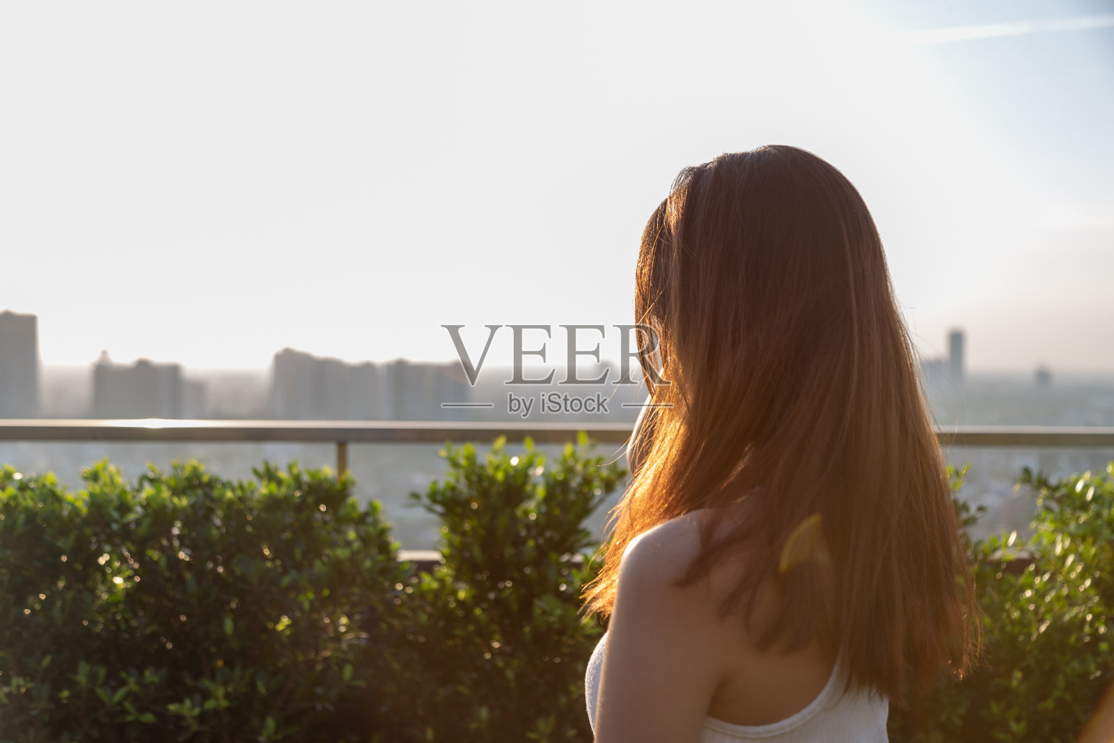 独自一人看日落，傍晚在高楼顶上欣赏美景，孤独美丽的年轻女子感到孤独，思考着她未来的生活，快乐的女孩在城市里享受着美丽的景色照片摄影图片