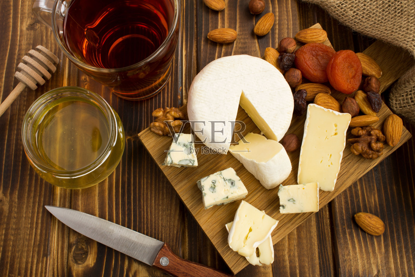 点心配上奶酪、茶和蜂蜜放在木砧板上照片摄影图片