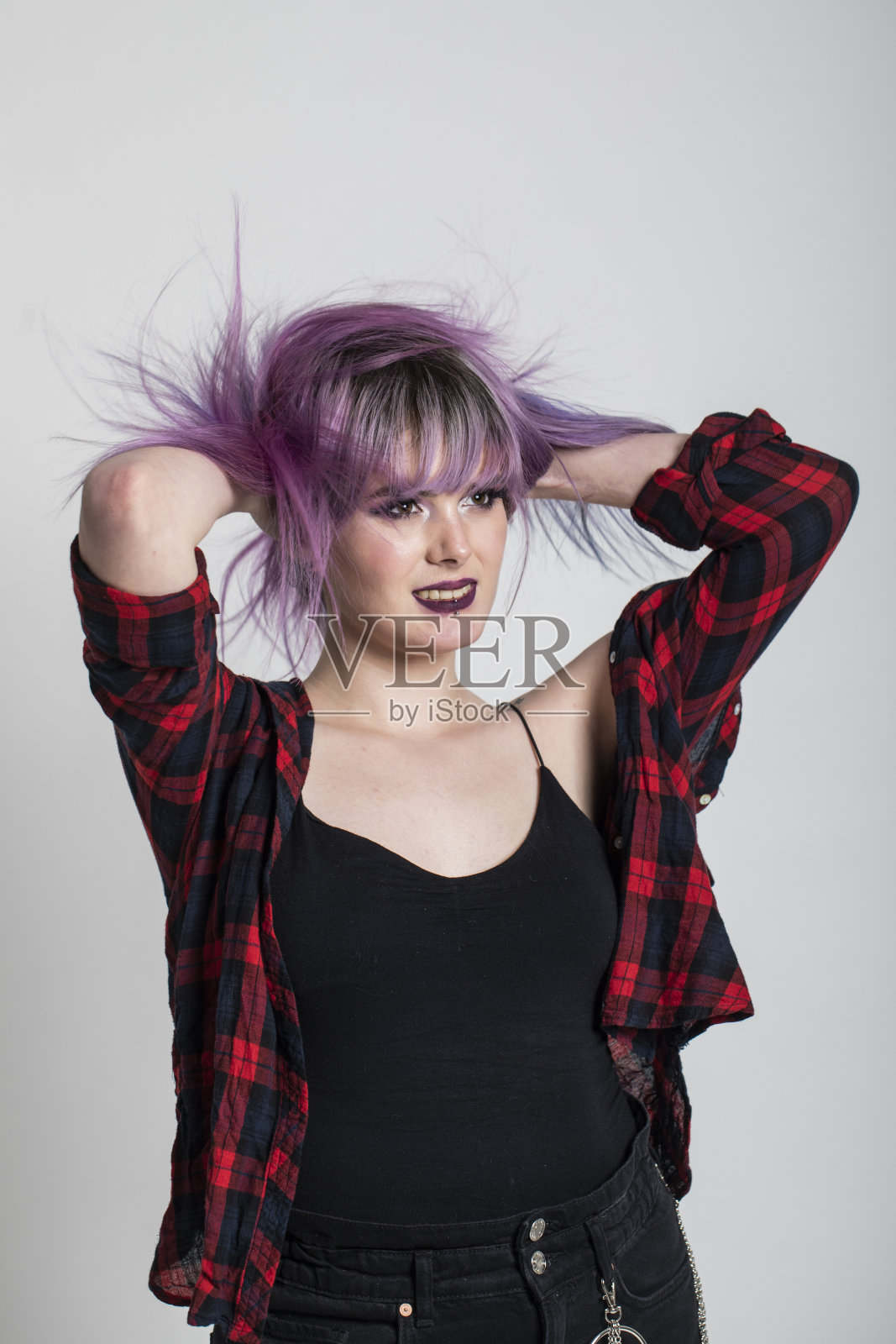 时髦的年轻女子与紫色的头发，笑，跳舞和有一个美好的时间在灰色的背景。照片摄影图片