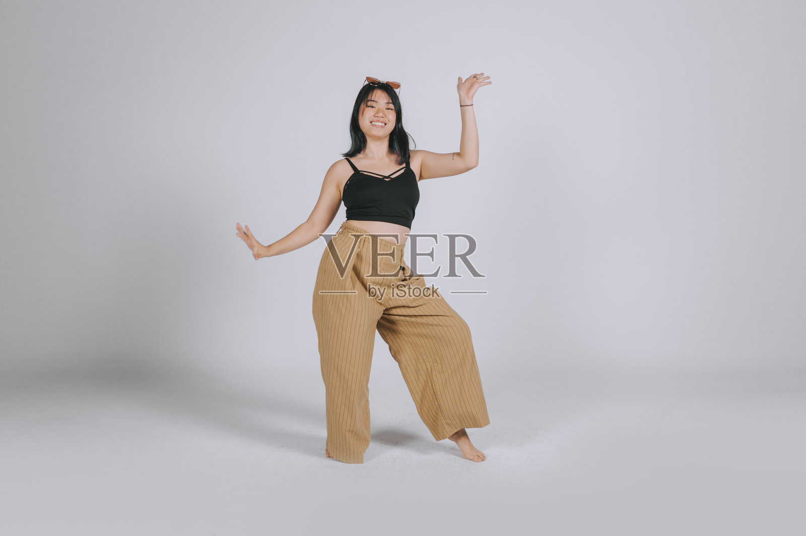 亚洲中国少女跳舞在工作室拍摄与灰色背景的乐趣照片摄影图片