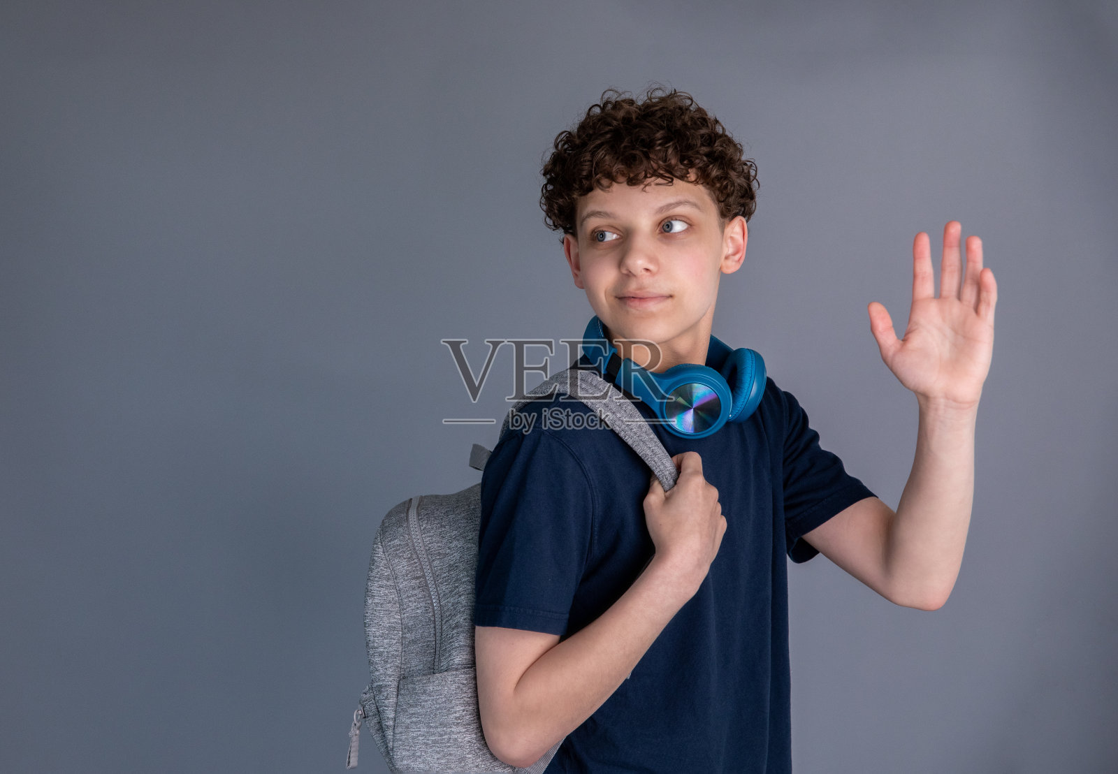 十几岁的男孩是学生，背着背包，戴着耳机照片摄影图片