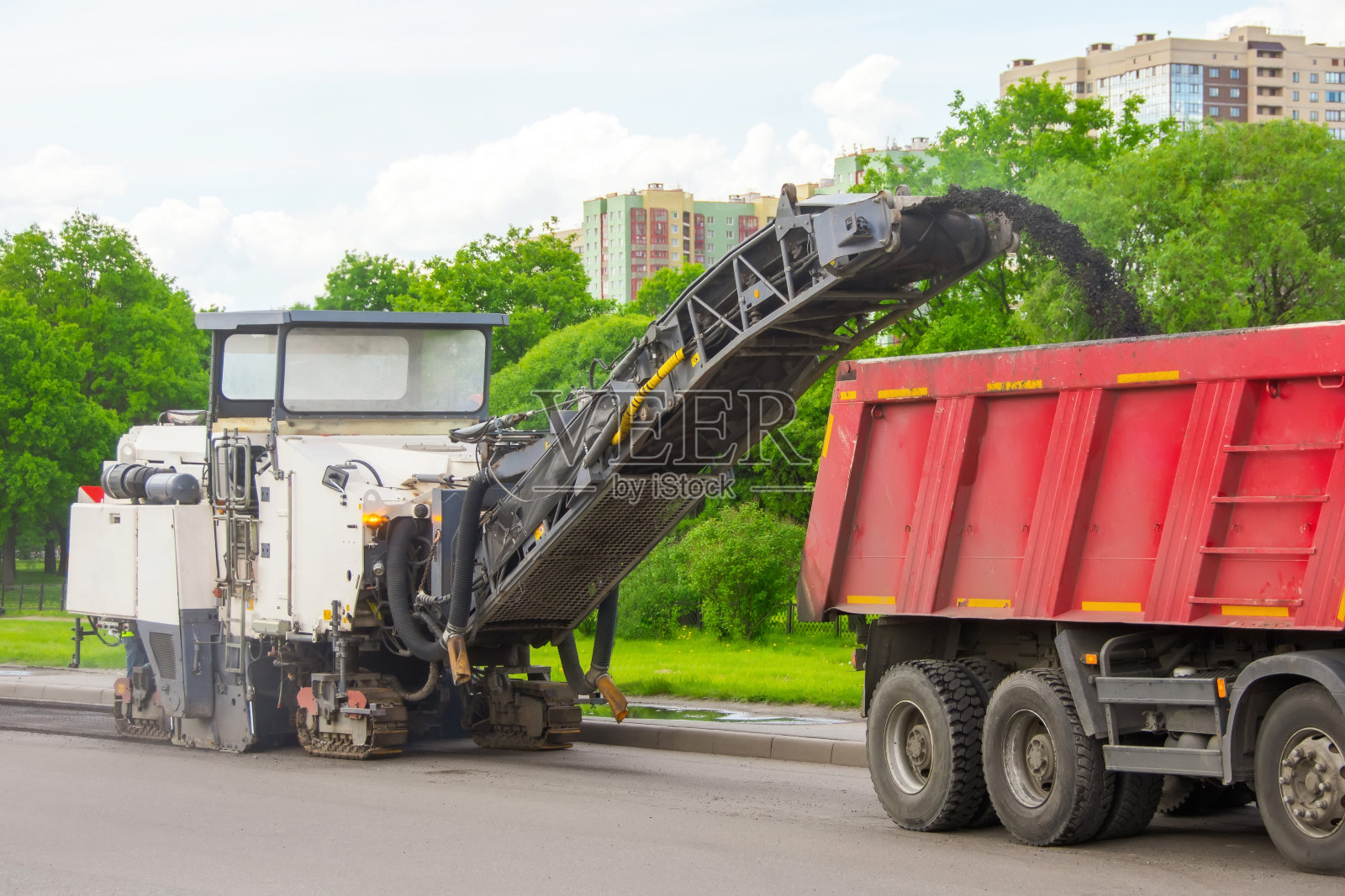 路面冷磨机将旧沥青清除并装入自卸卡车。路面沥青路面的修补。照片摄影图片