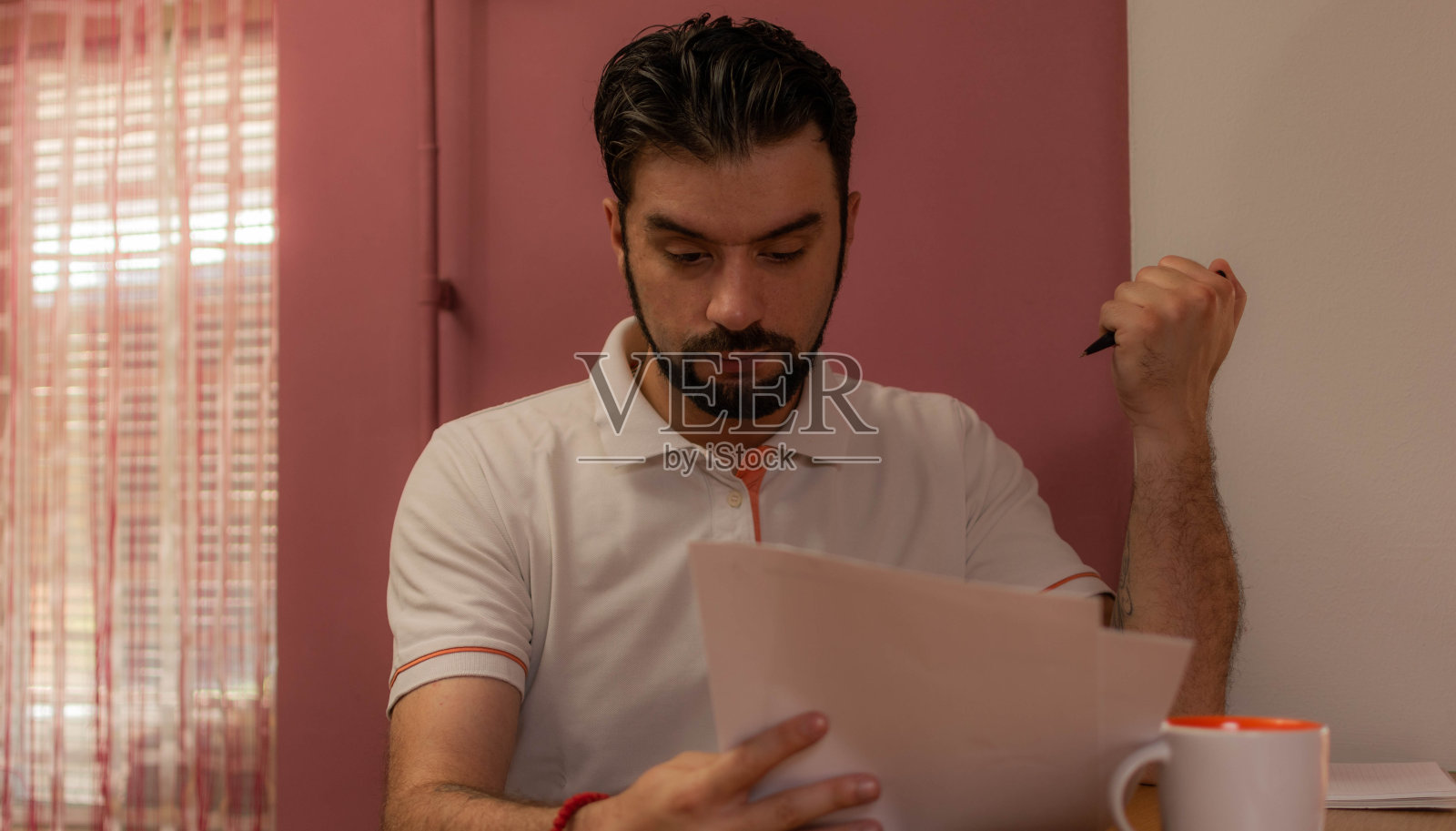 一个年轻人坐在家里，工作，喝咖啡，看书。生活方式，在家工作。照片摄影图片