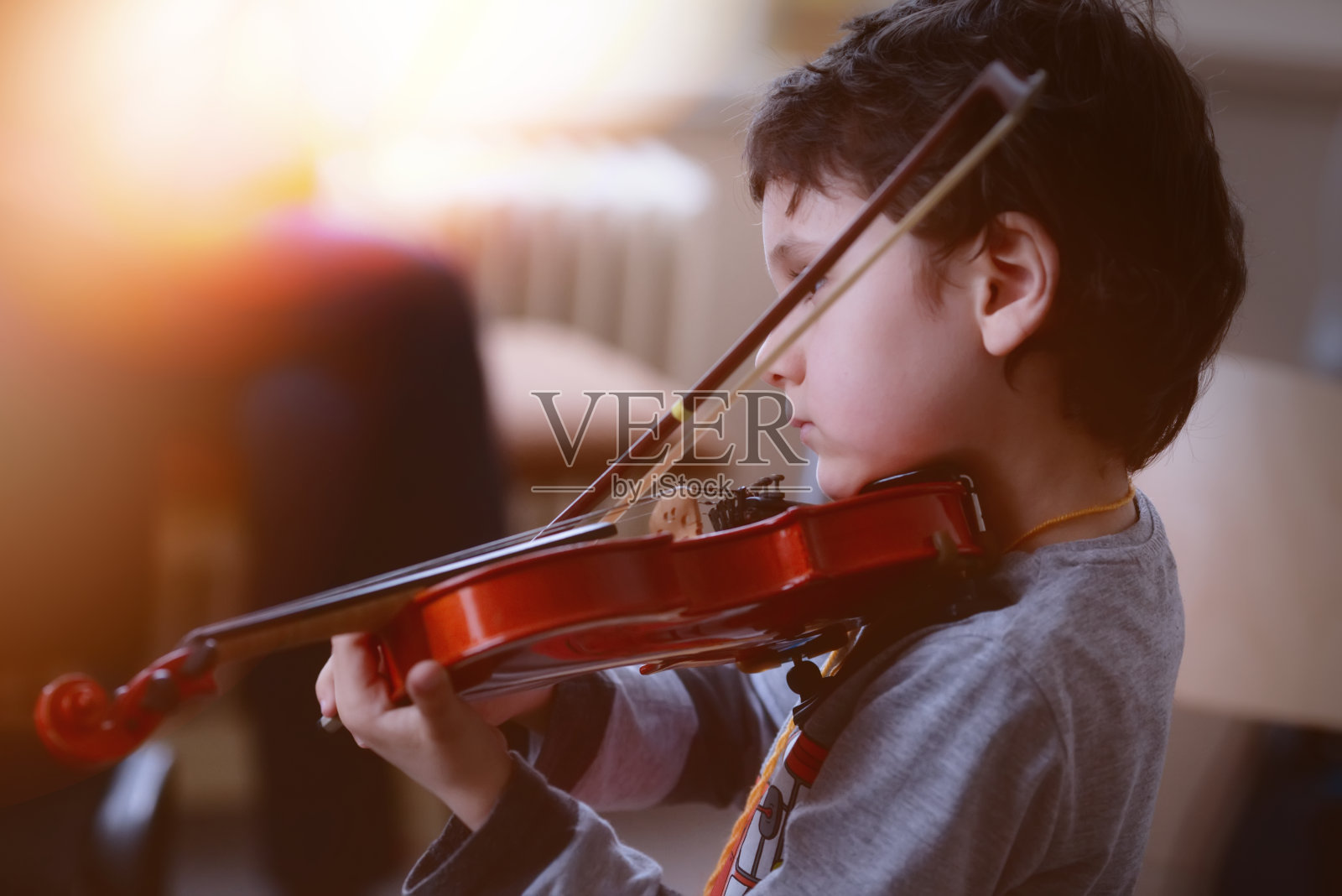 孩子在房间里拉小提琴照片摄影图片