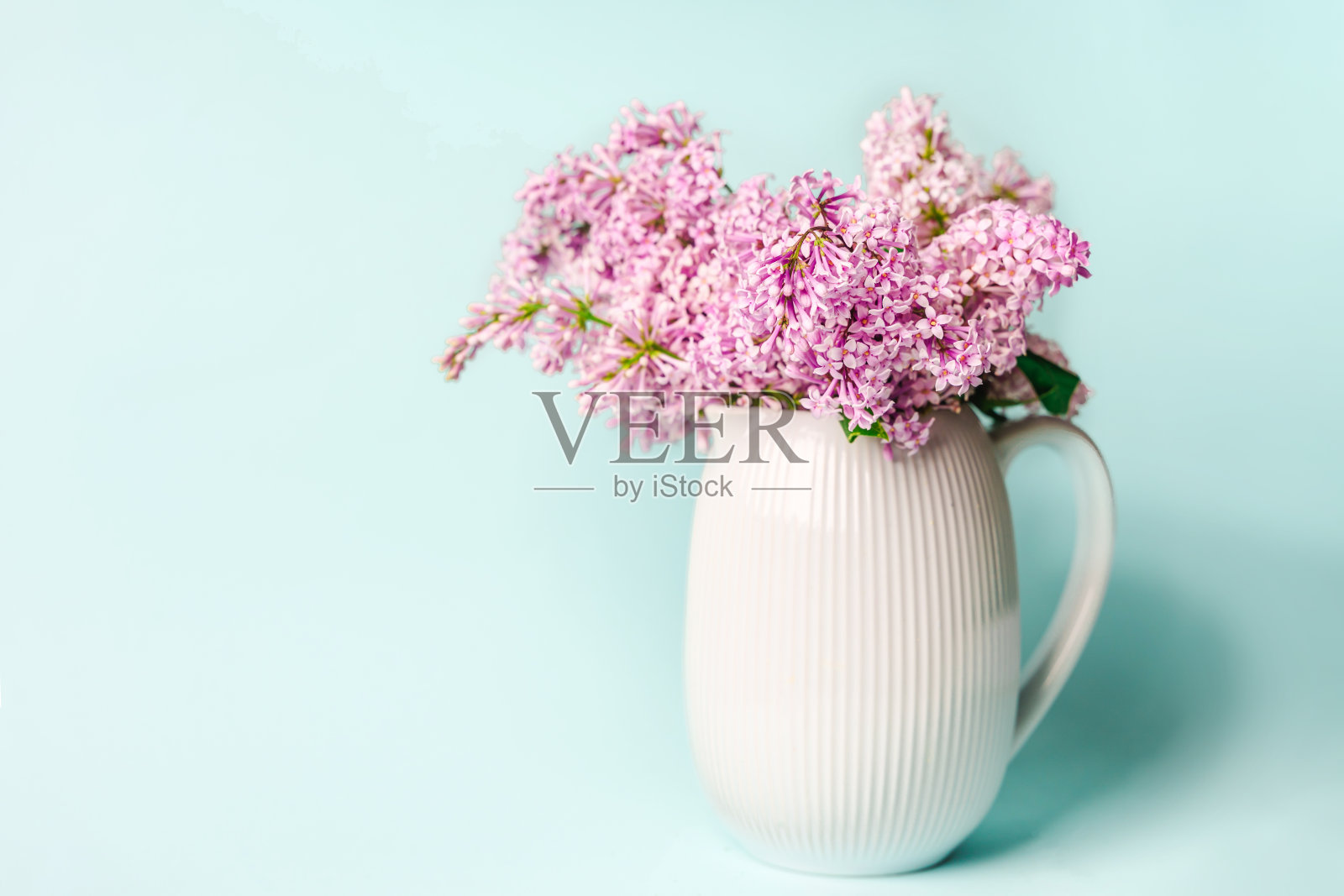 美丽的花卉构图在蓝色的背景和一个花瓶与丁香照片摄影图片