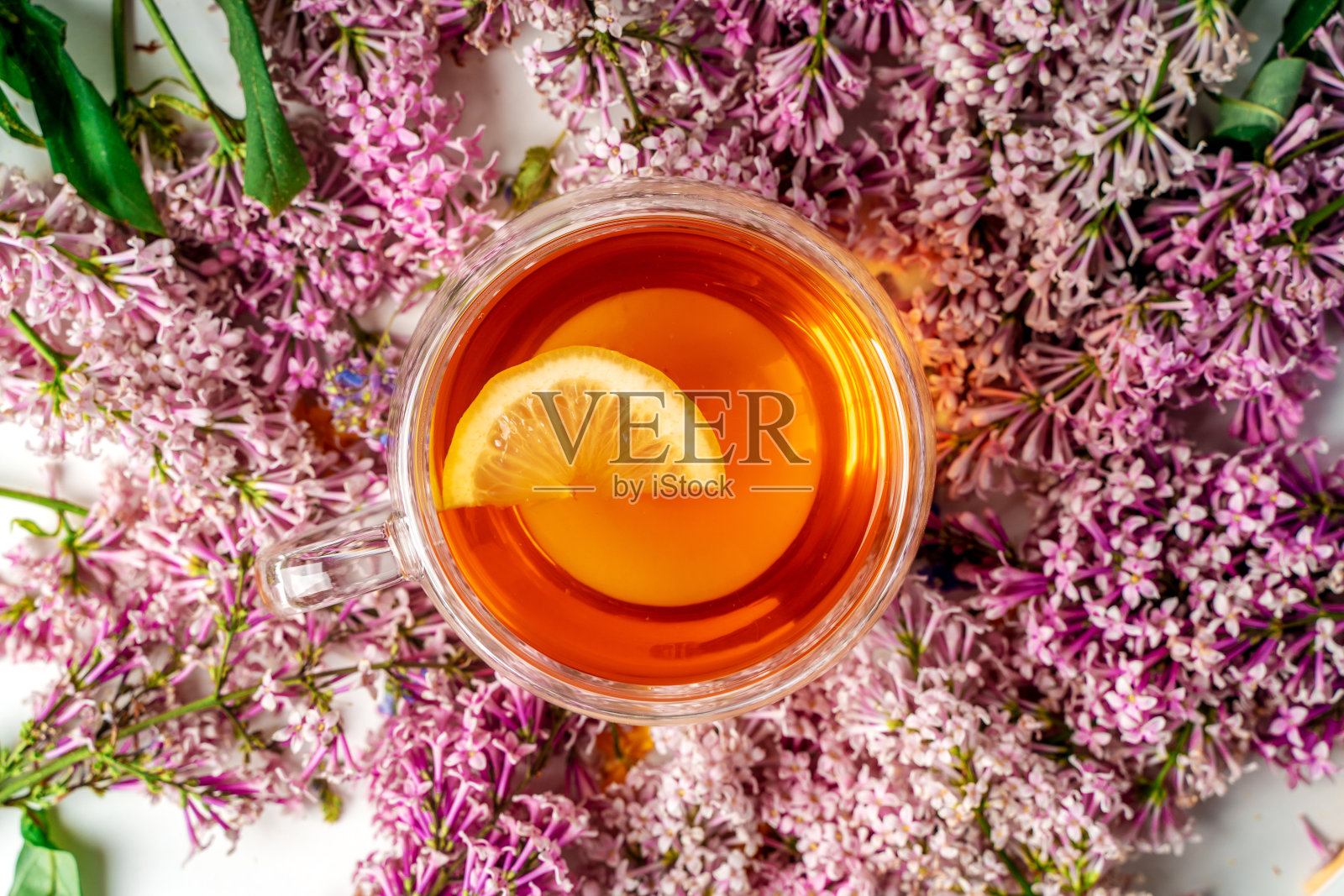 一杯柠檬丁香茶。温馨浪漫的花卉背景与拷贝空间。平的。照片摄影图片