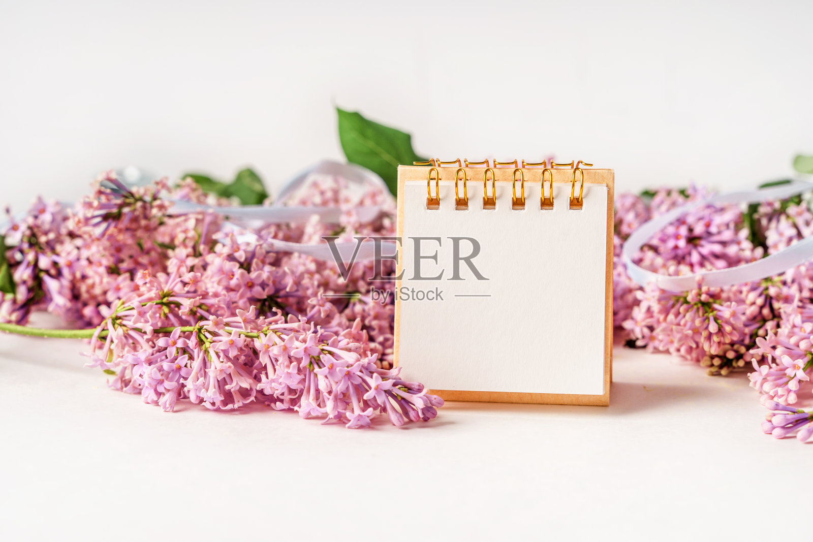 一个美丽的花的组成和一个空白的纸记事本的文本。花的春天背景与丁香。本空间照片摄影图片