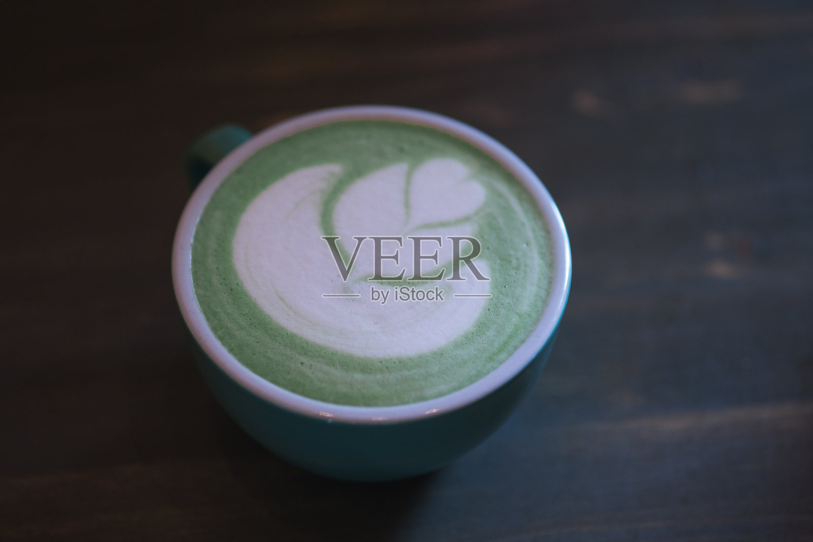 桌上放着一杯绿色抹茶拿铁茶，拿铁艺术照片摄影图片