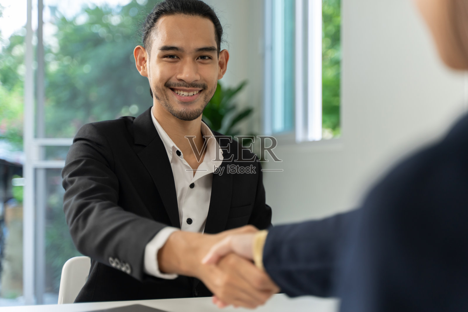 迷人的年轻亚洲商人在办公室与女商人握手。照片摄影图片