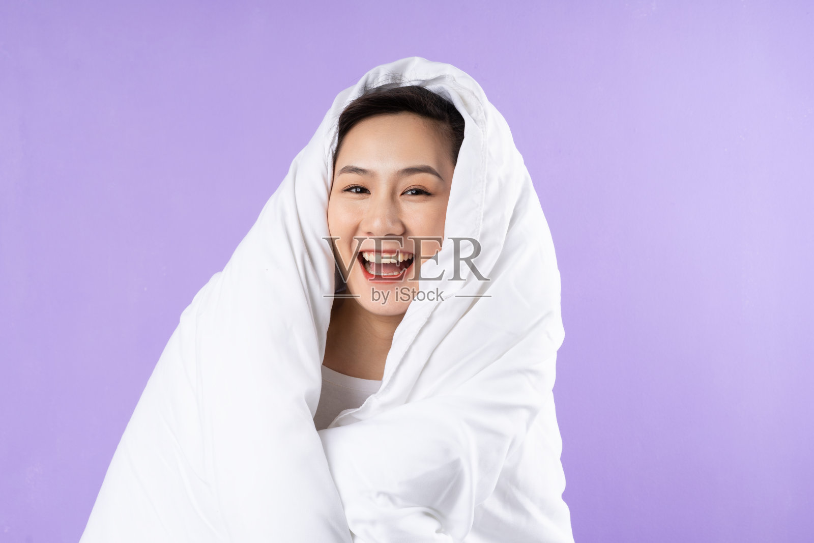 亚洲妇女蜷缩在毯子在紫色的背景照片摄影图片