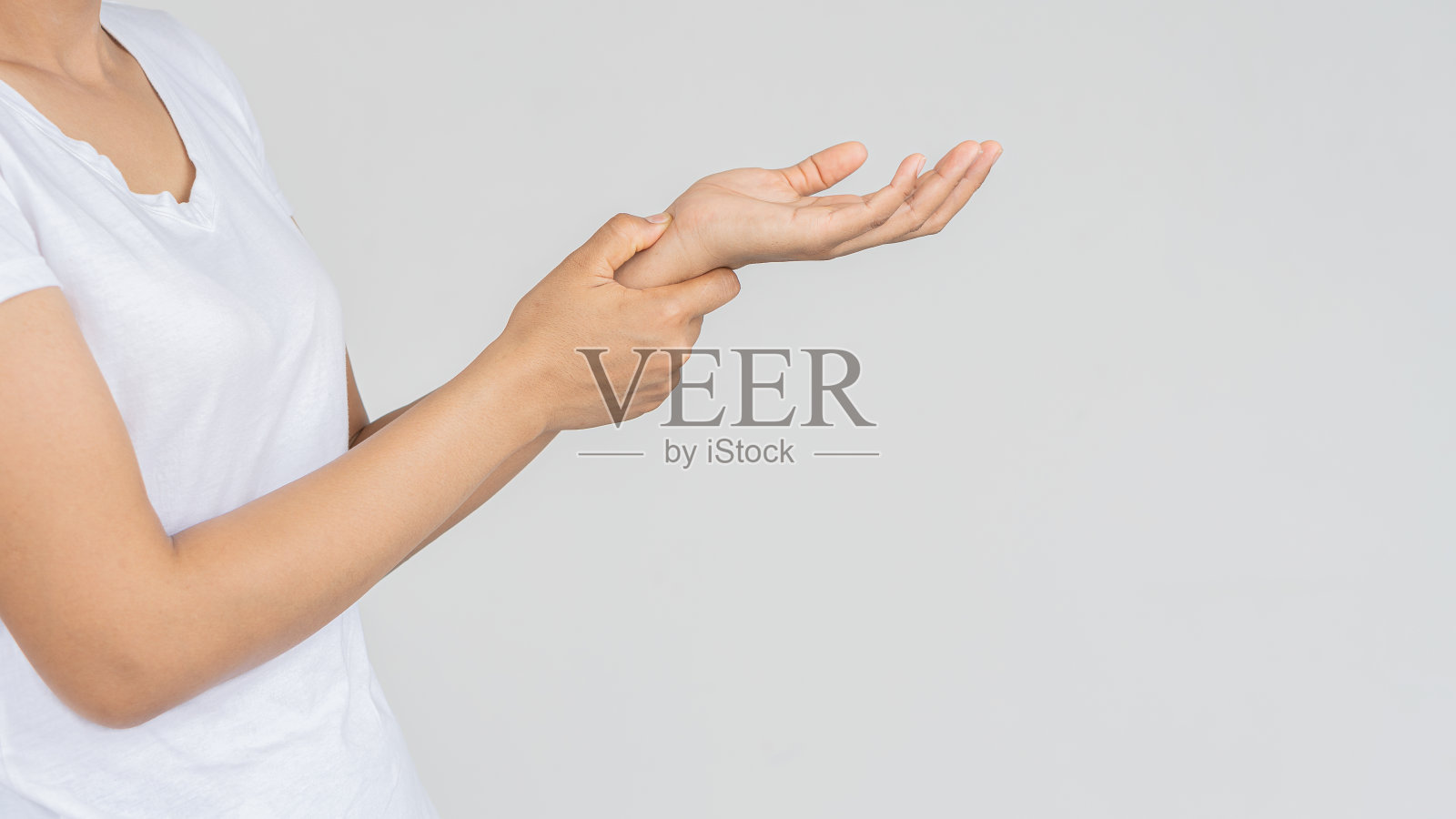 年轻女子手腕疼痛站在白色背景，医学概念照片摄影图片