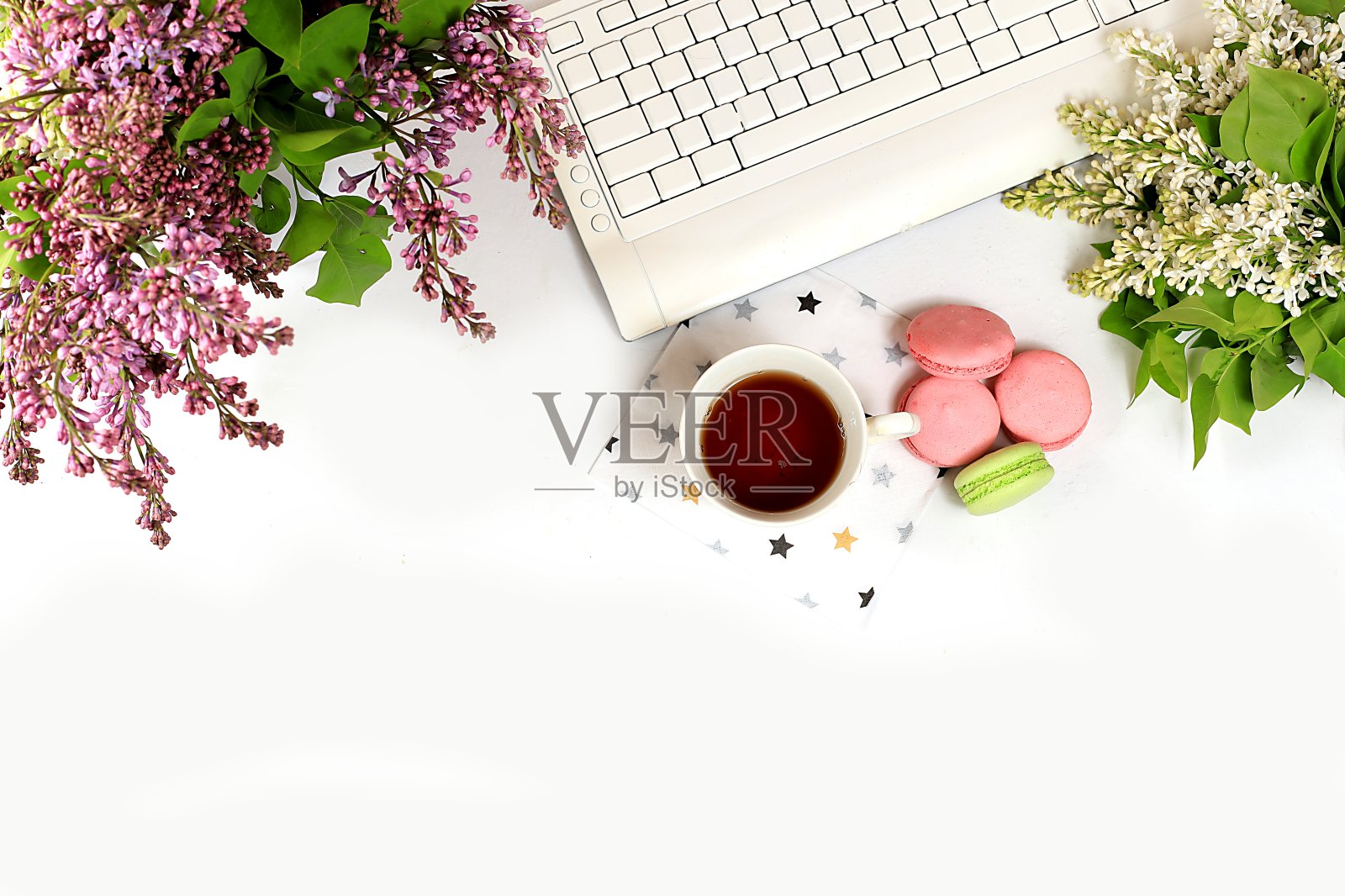 现代女性的桌面，家庭办公室，一杯花茶和饼干在一个淡紫色的花轻桌上。健康早餐，健康生活理念，照片摄影图片