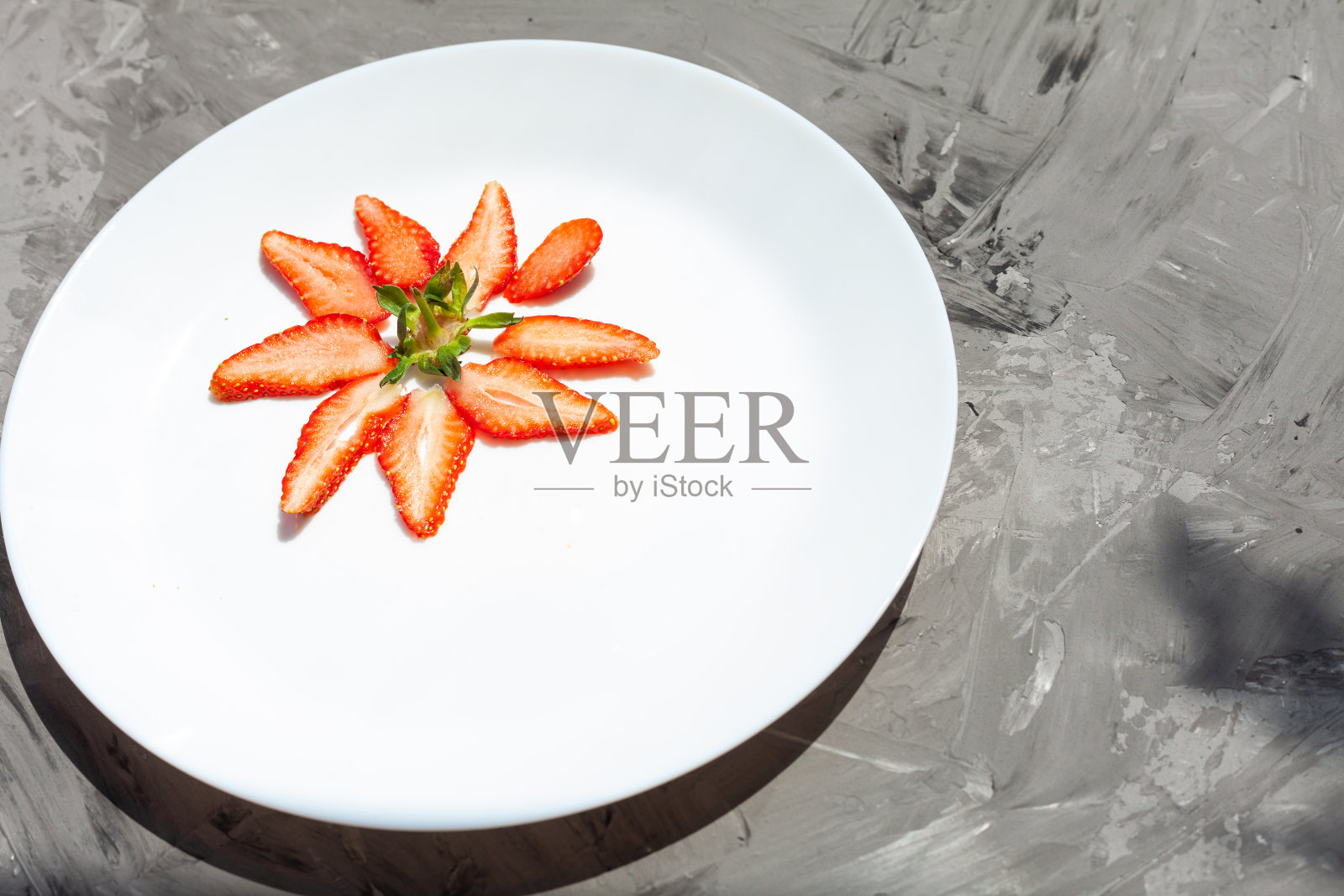 草莓片呈花的形状摊在一个白色盘子里照片摄影图片