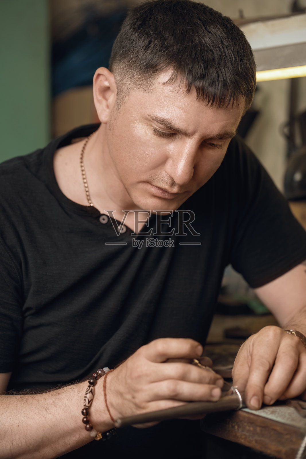 一个珠宝商在作坊里用宝石修理金戒指的肖像照片摄影图片