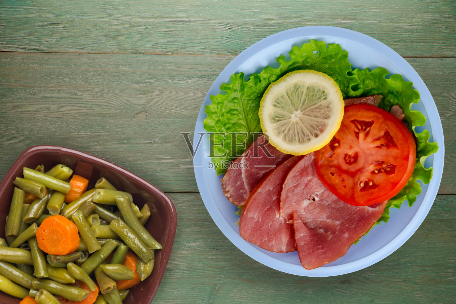 火腿配沙拉，西红柿和柠檬装在一个盘子里。照片摄影图片