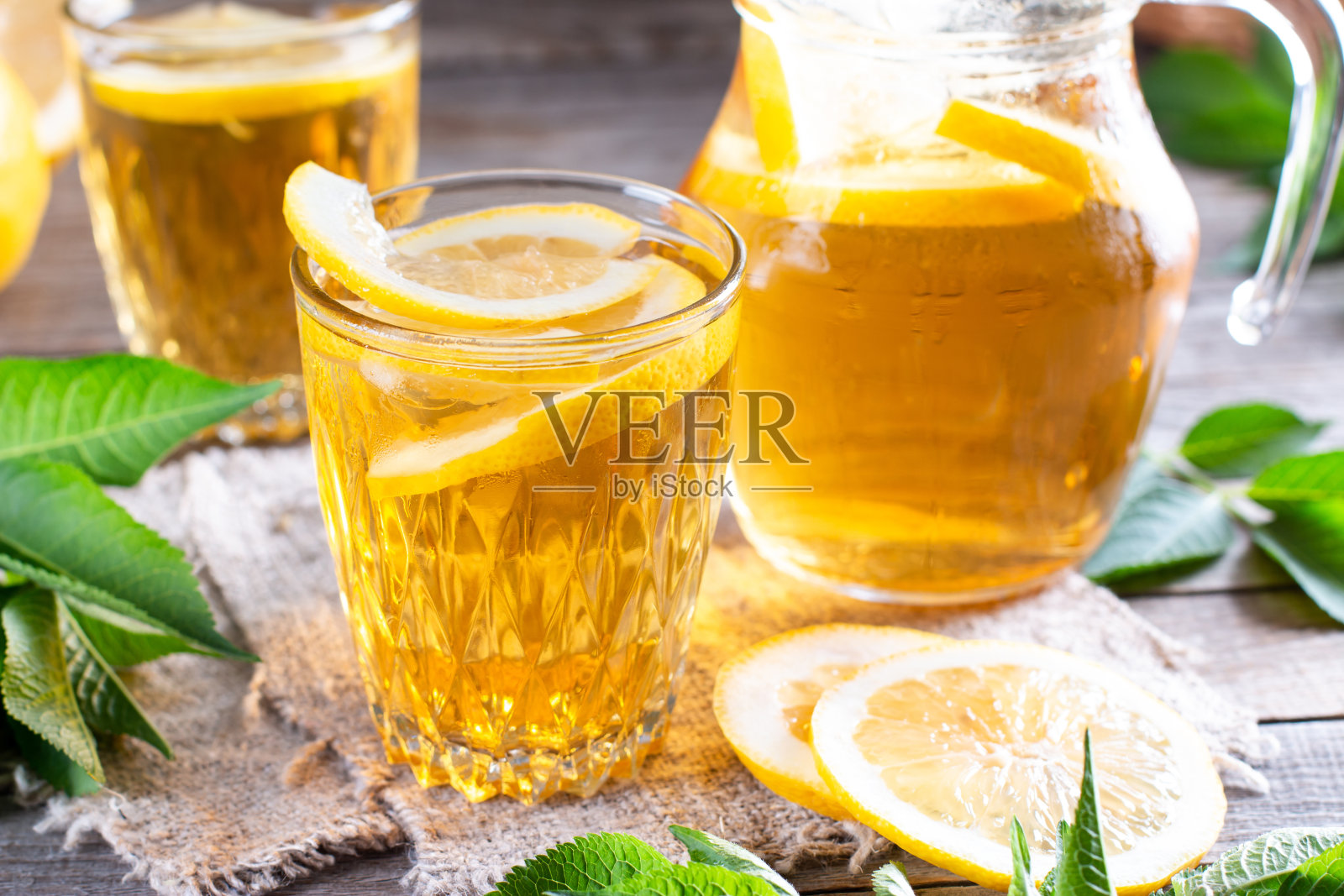 清爽的饮料，冰茶和石灰楔玻璃放在木桌上。夏季饮料。照片摄影图片