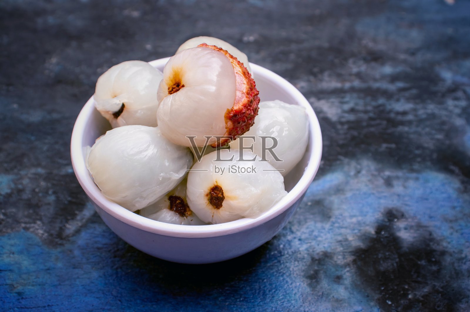 特写的多汁荔枝或荔枝水果在一个碗孤立的木制背景照片摄影图片