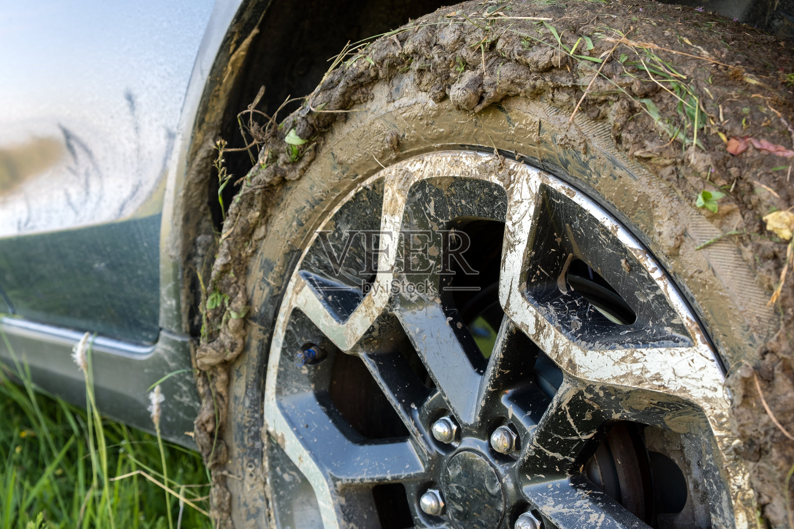 靠近肮脏的公路汽车车轮与肮脏的轮胎覆盖着黄色的泥。照片摄影图片