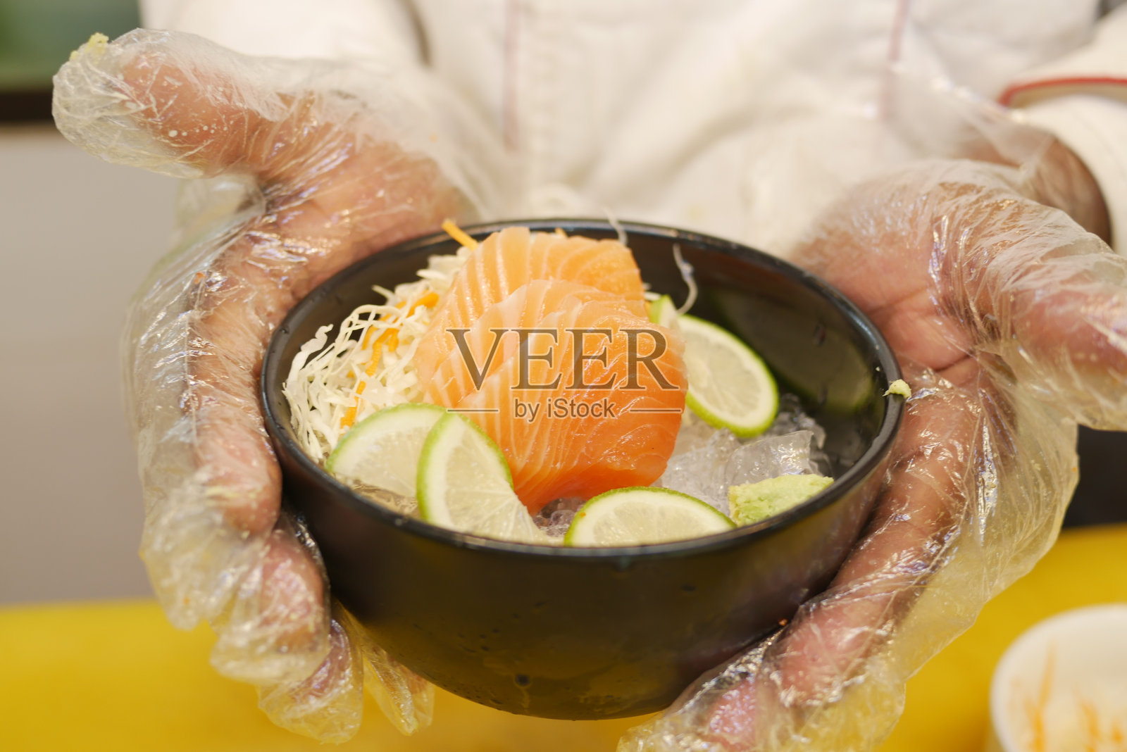 酋长端着一碗加冰柠檬的生三文鱼片。照片摄影图片