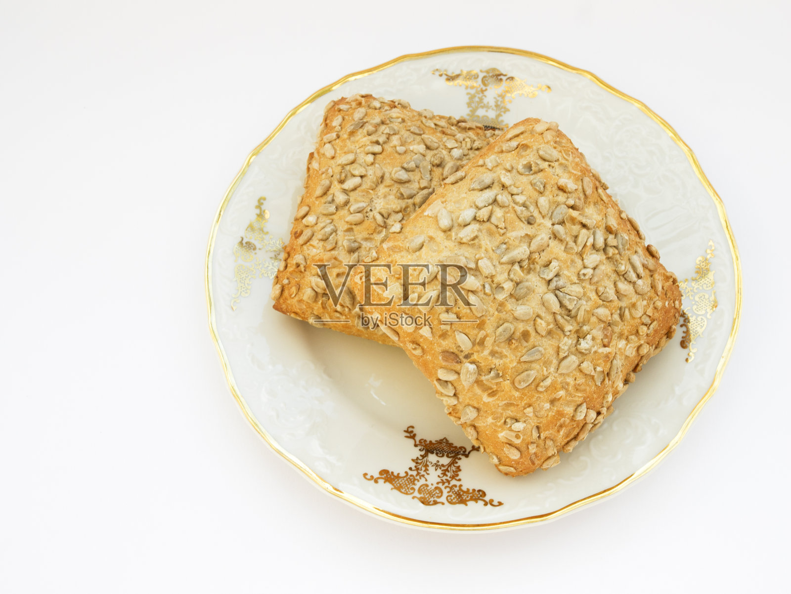 向日葵包在瓷盘上，白色的背景照片摄影图片