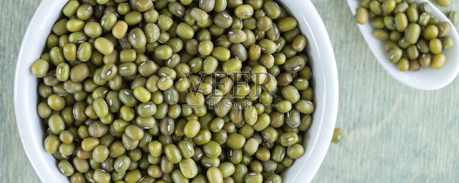 横幅与顶视图上的绿豆，白色盘子与勺子。靠近mung在一个绿色的木制背景照片摄影图片