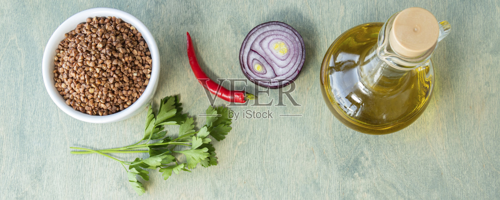 带有食谱或食物成分或营养概念的横幅。荞麦与香料和橄榄油在绿色木质背景。白盘荞麦，辣椒，大蒜和欧芹。平躺照片摄影图片