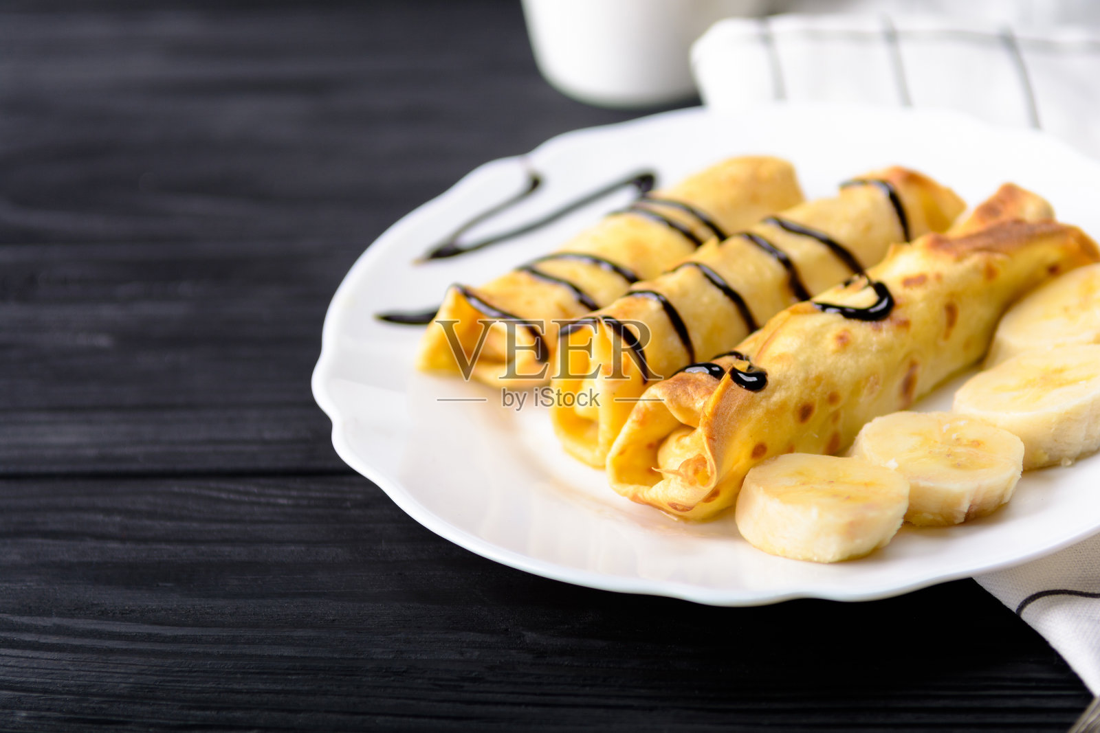 黑木色背景下的香蕉巧克力浆煎饼。照片摄影图片