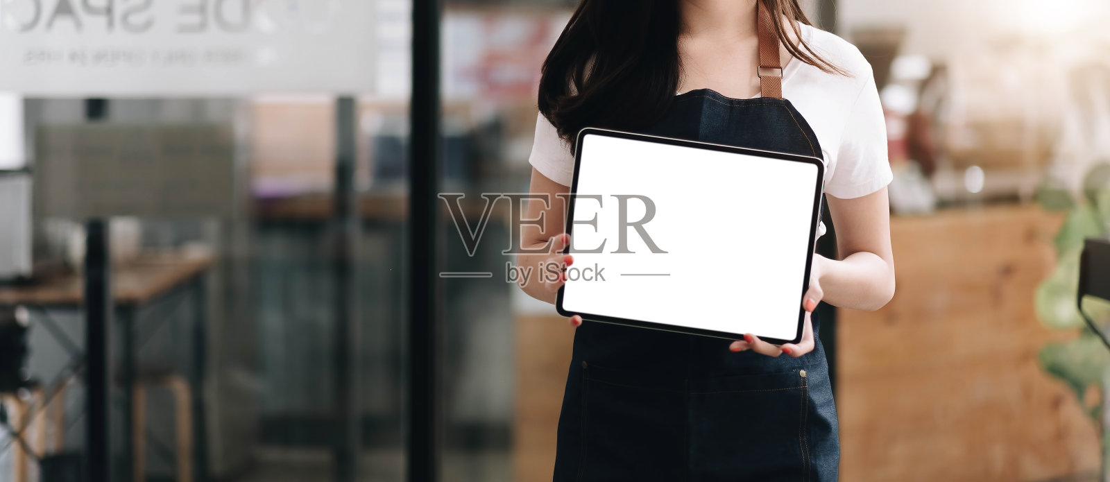近距离观看咖啡师展示的空白平板电脑，双手握在咖啡店柜台吧台前，模拟空间显示菜单或设计。照片摄影图片