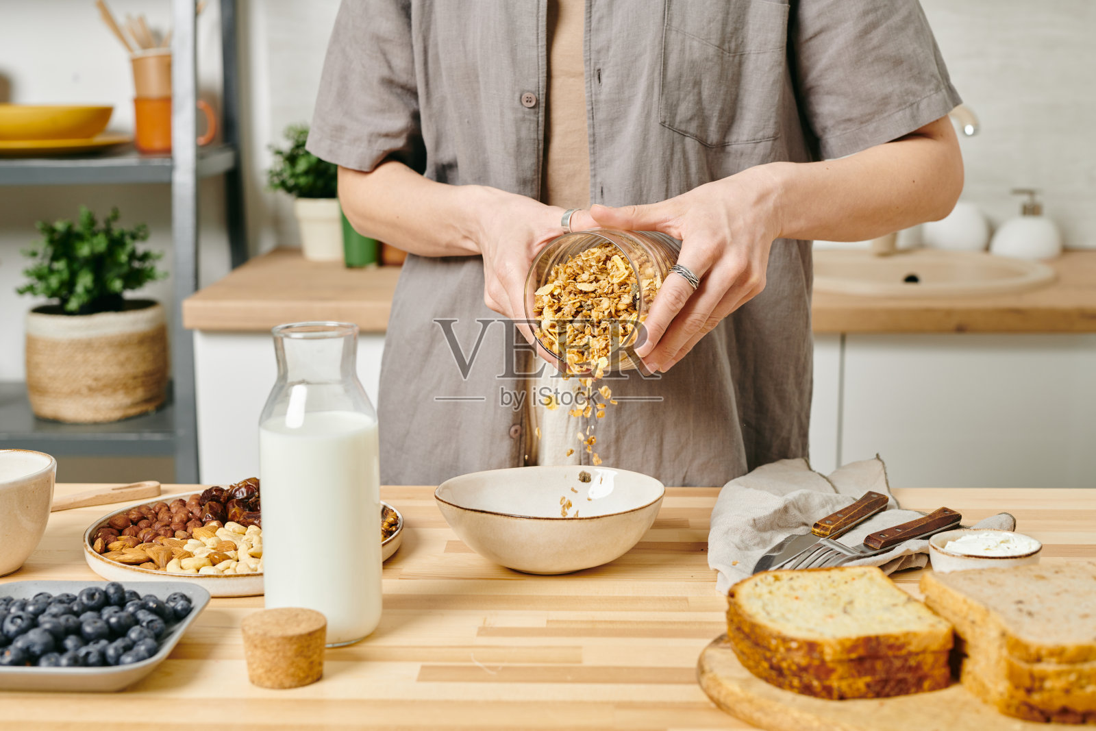 年轻女性，穿着休闲服，把麦片放进碗里照片摄影图片