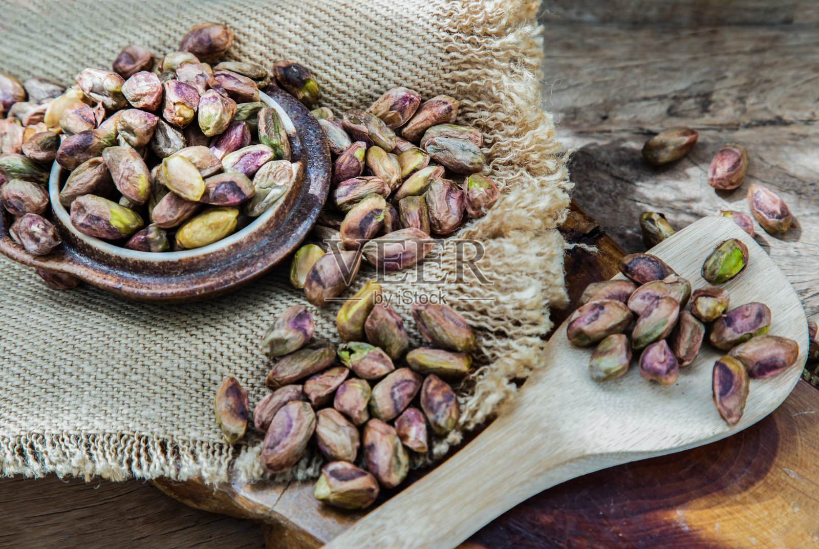 一堆剥了壳的开心果，堆在粗布上，背景是古老的木制品。黄连木的干燥种子和成熟果实，照片摄影图片