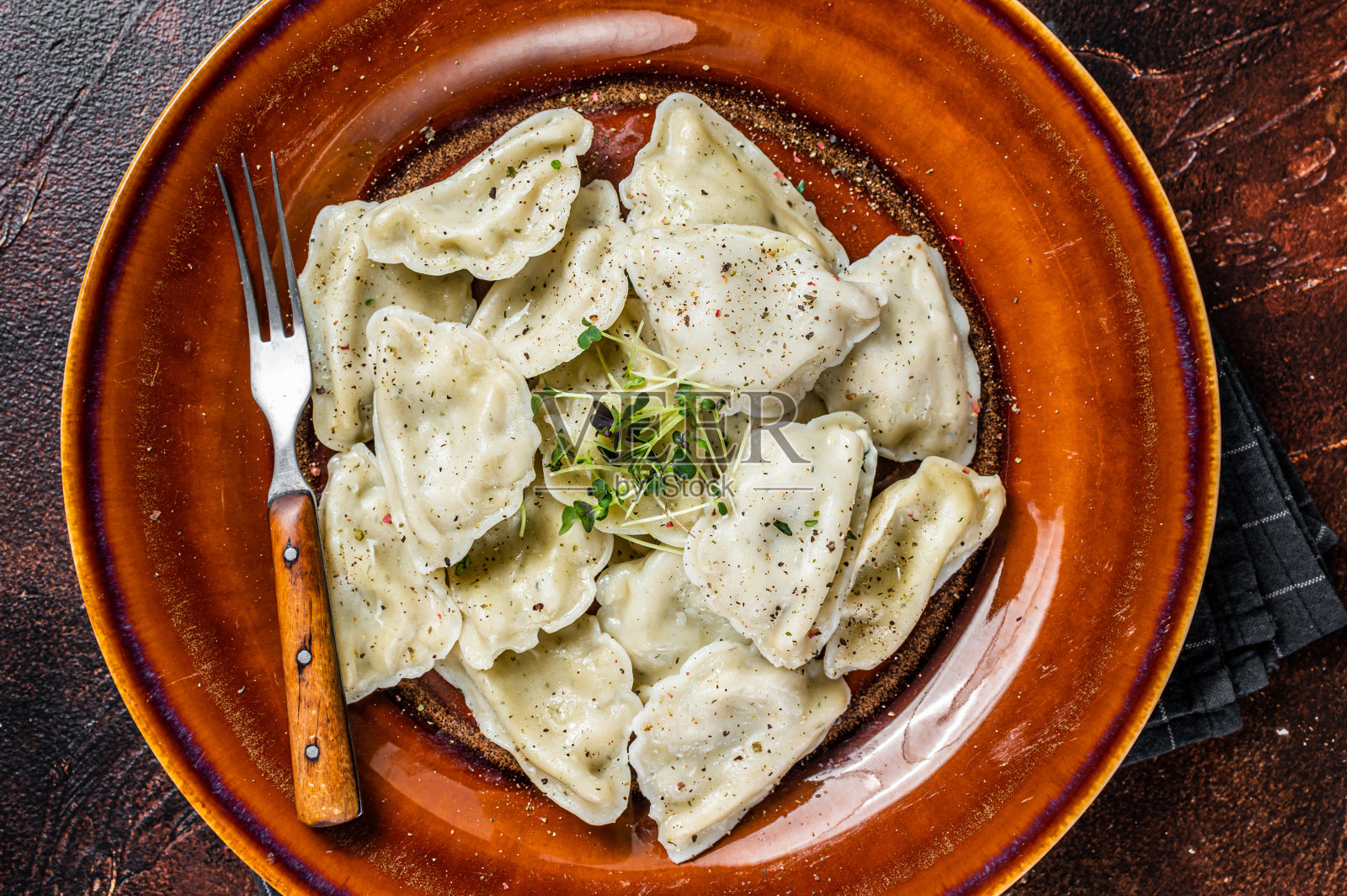 波兰饺子配土豆，香草和黄油。黑暗的背景。俯视图照片摄影图片