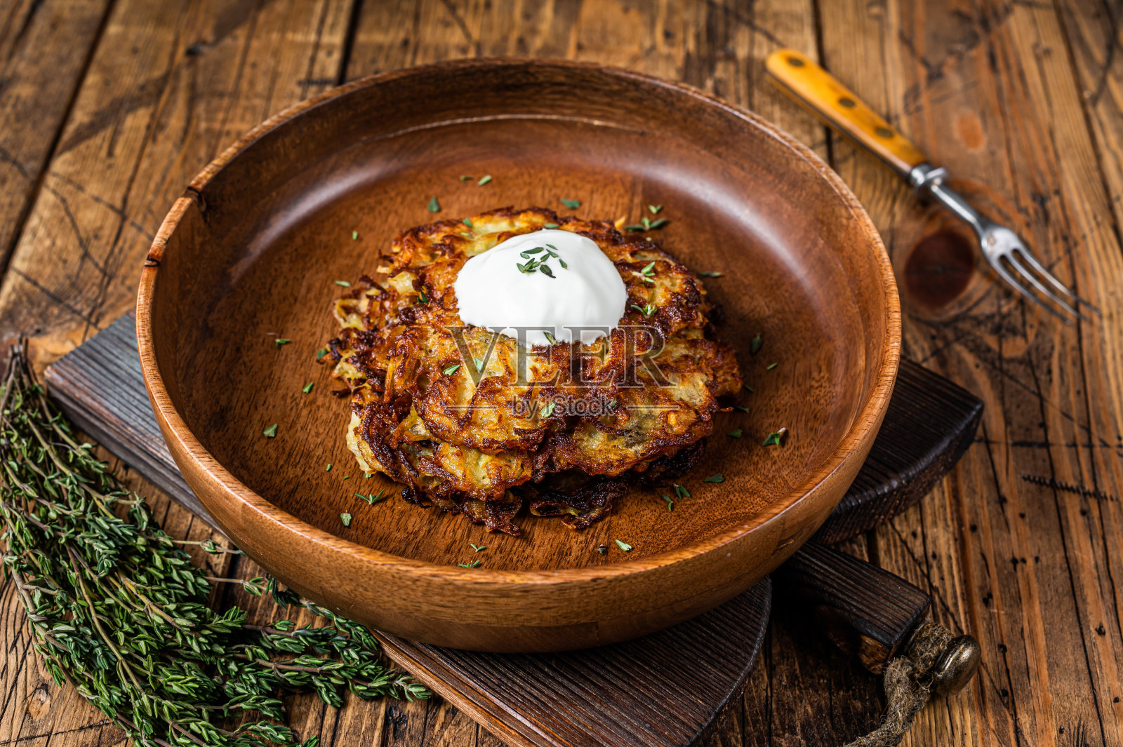 用木盘盛着烤土豆煎饼或香草油饼。木制背景。俯视图照片摄影图片