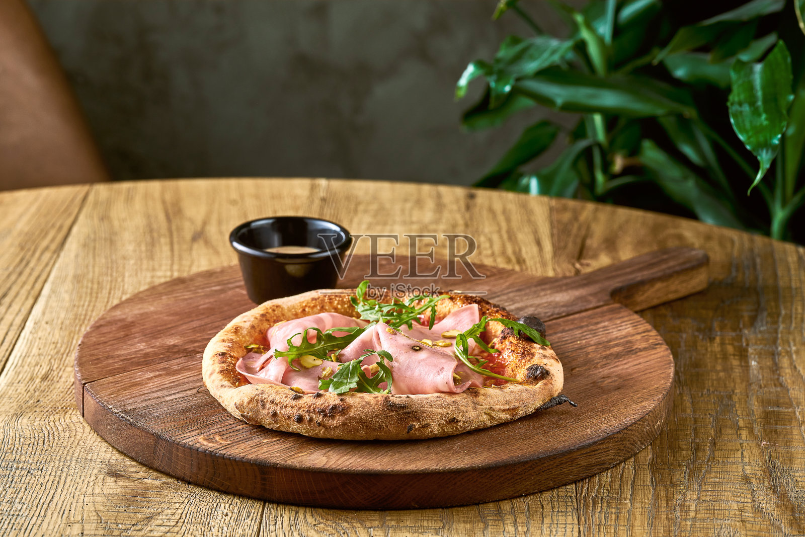 披萨配上香肚，芝麻菜和开心果放在木板上。意大利美食照片摄影图片