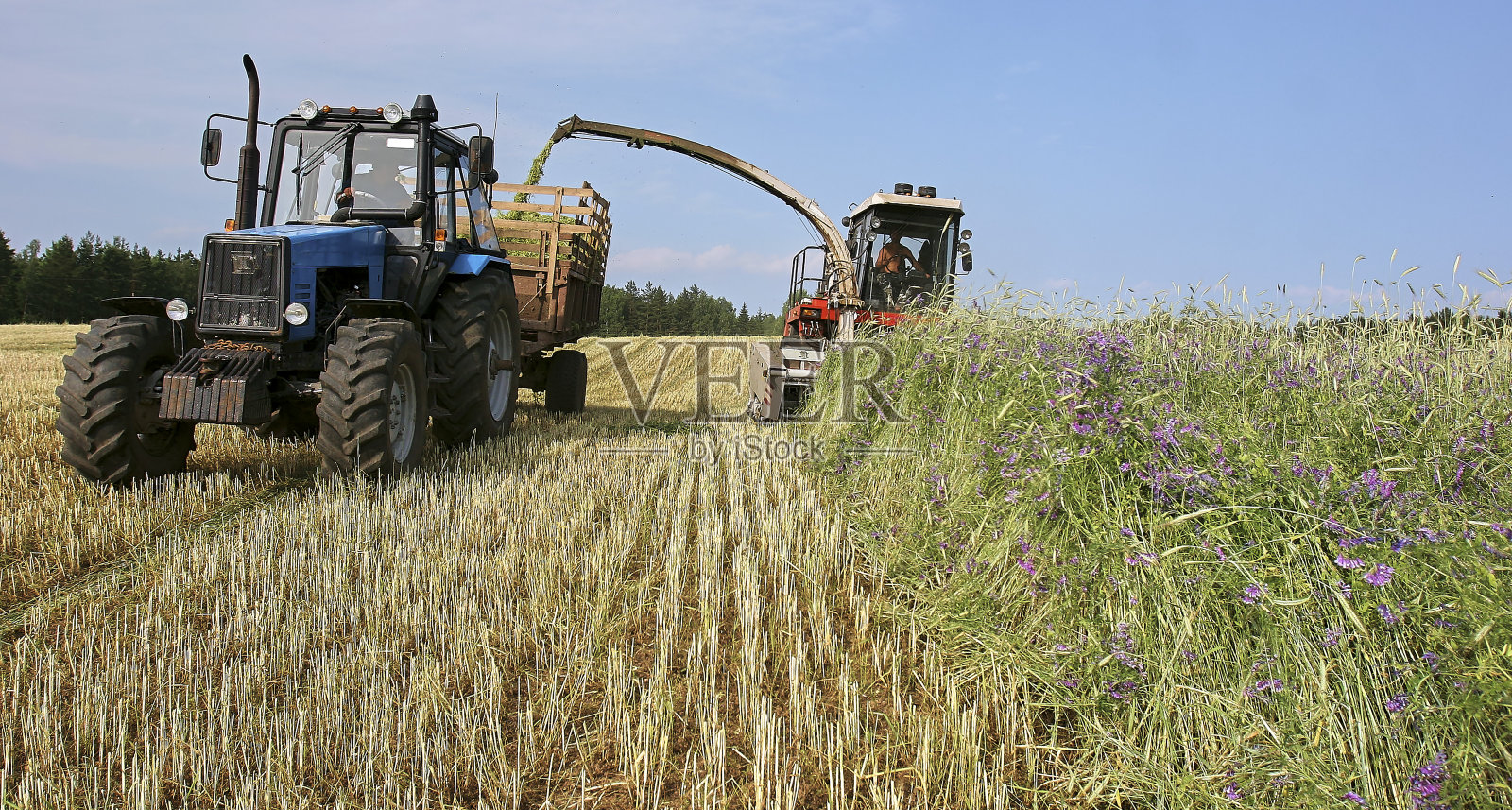 草地上有收割机和拖拉机。照片摄影图片