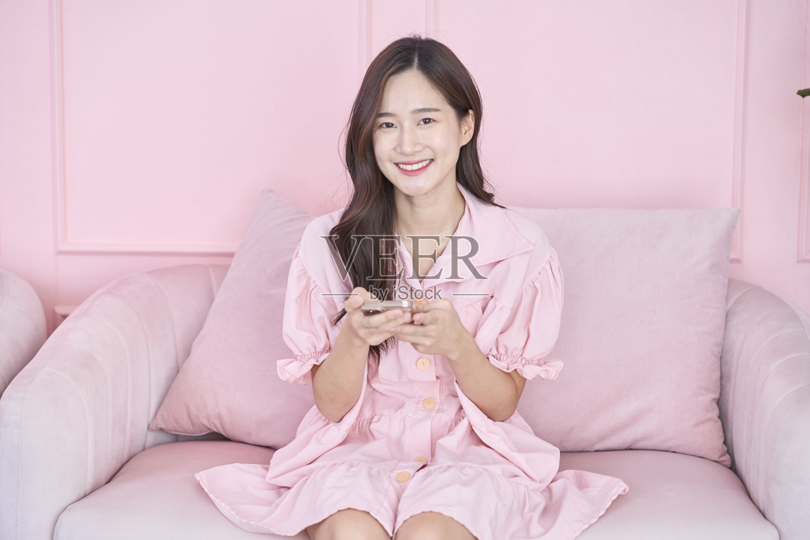 快乐的亚洲女商人在粉色房间使用手机照片摄影图片