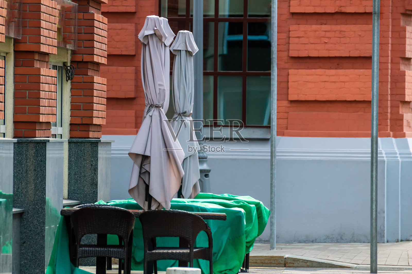 街上的咖啡馆关门了。雨伞卷起来，桌子上铺着布。没有人。大流行。照片摄影图片
