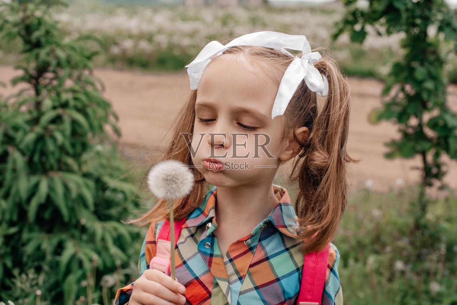 一个孩子在空中吹着蒲公英。照片摄影图片